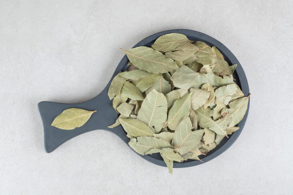 Dried green bay leaves on a wooden plate. High quality photo